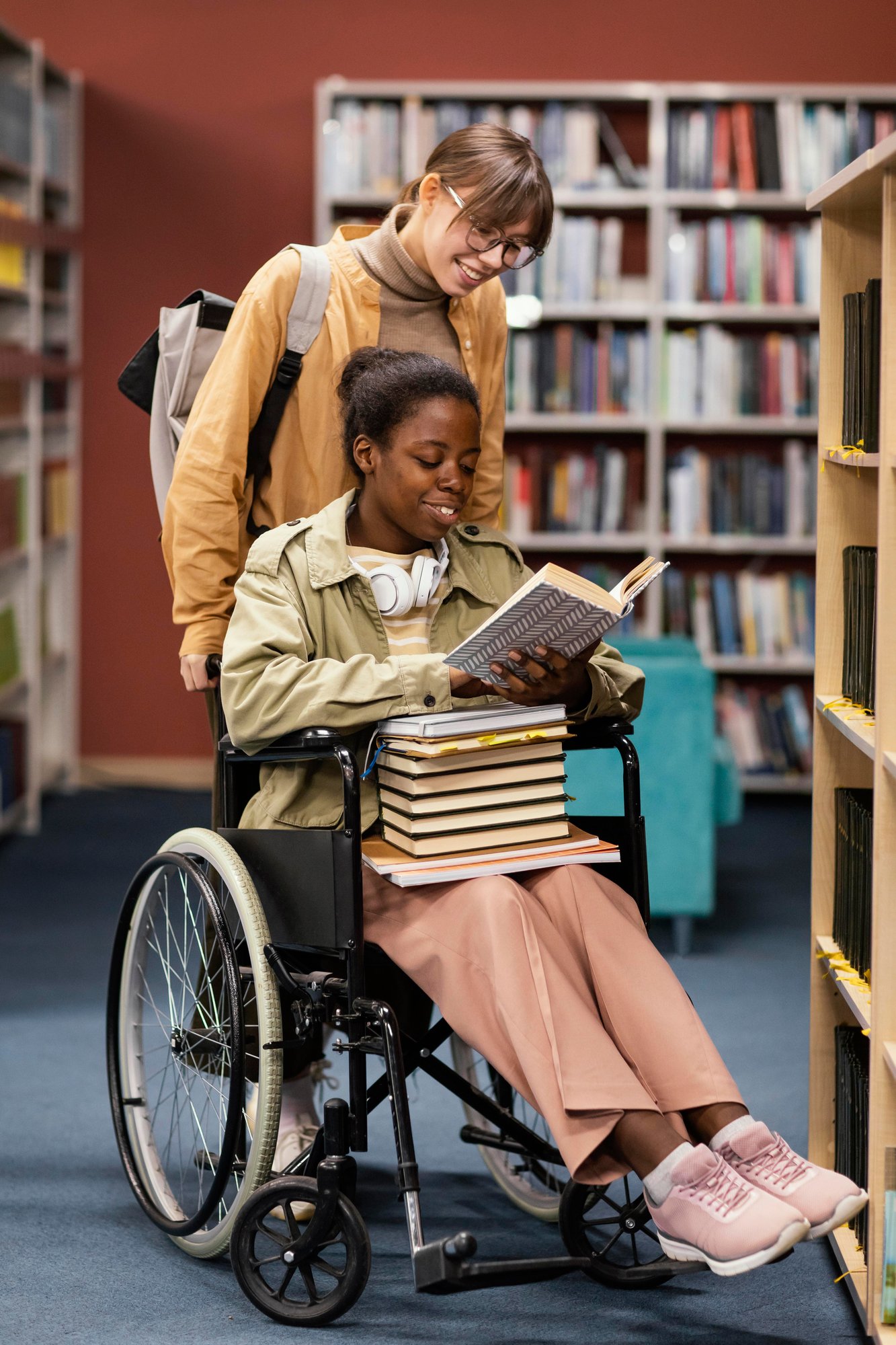 girl-helping-her-colleague-wheelchair-choose-book-project